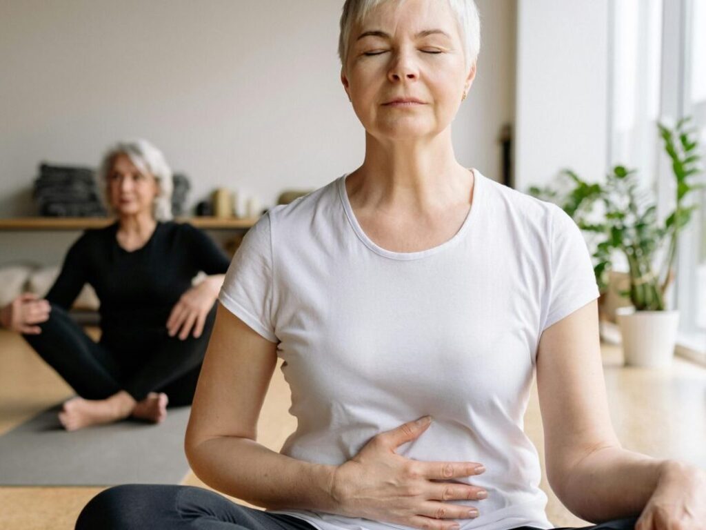 Elderly women practicing yoga indoors for health and wellness.